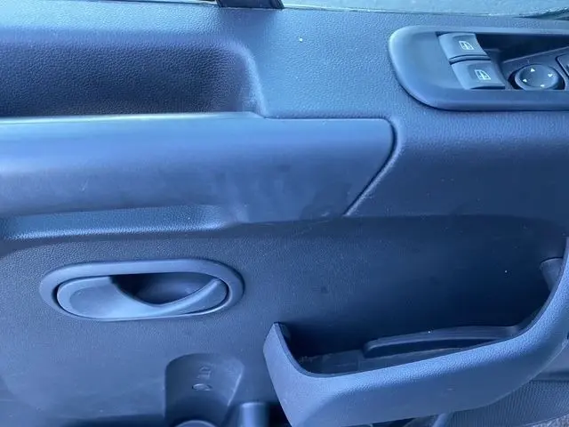 Détail de la porte intérieure côté conducteur du Renault Master blanc, avec poignée, commandes de vitres et rangement intégré.