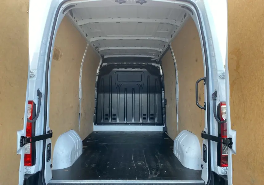 Vue arrière du Renault Master blanc 2022 montrant l’intérieur vide et spacieux de la zone de chargement avec cloison pleine noire.
