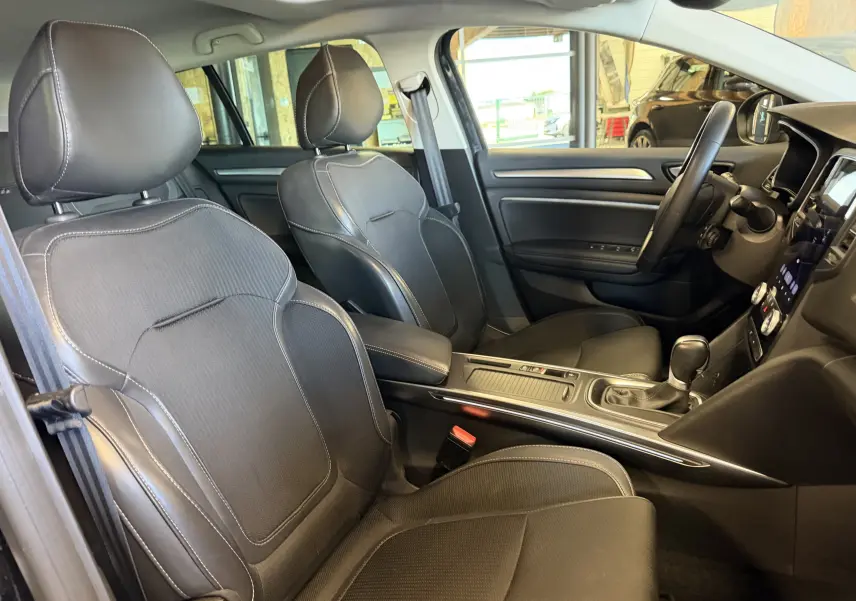 Vue intérieure côté conducteur de la Renault Mégane Estate 2024 avec sièges noirs et console centrale moderne.