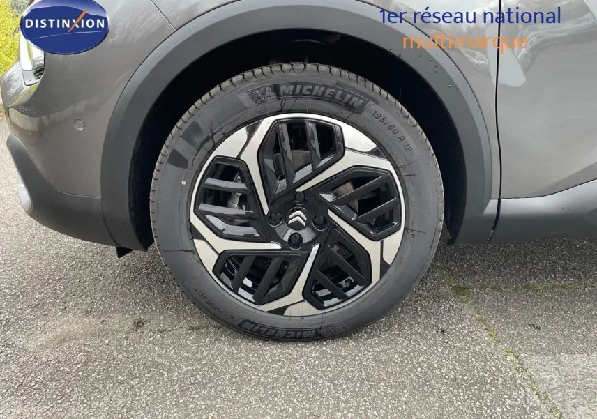Gros plan sur la roue avant gauche d'une Citroën C4 gris platinium métal avec jante alliage noire et argent.