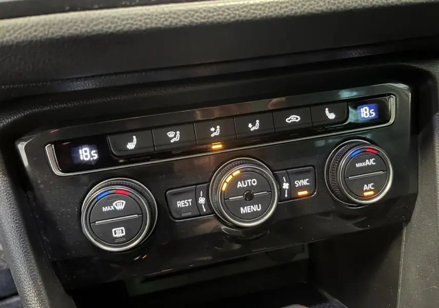 Gros plan sur la console de climatisation automatique du Volkswagen Tiguan blanc, avec réglages digitaux à 18,5°C.