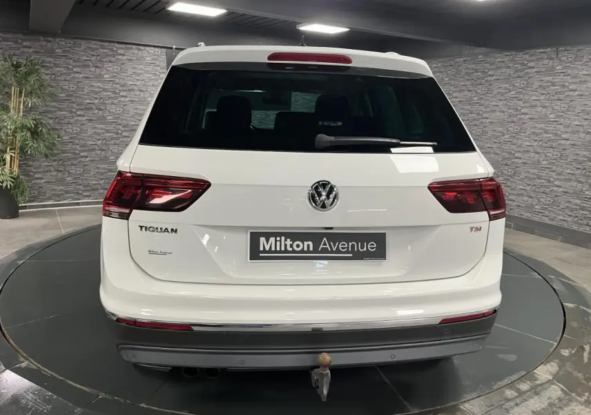 Vue arrière d'un Volkswagen Tiguan blanc avec crochet d'attelage escamotable et feux arrière LED 3D dans un showroom.