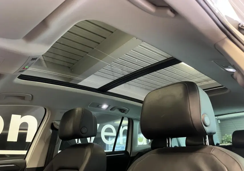 Intérieur du Volkswagen Tiguan 2017 vu des sièges avant, toit ouvrant panoramique et sièges cuir noirs visibles.