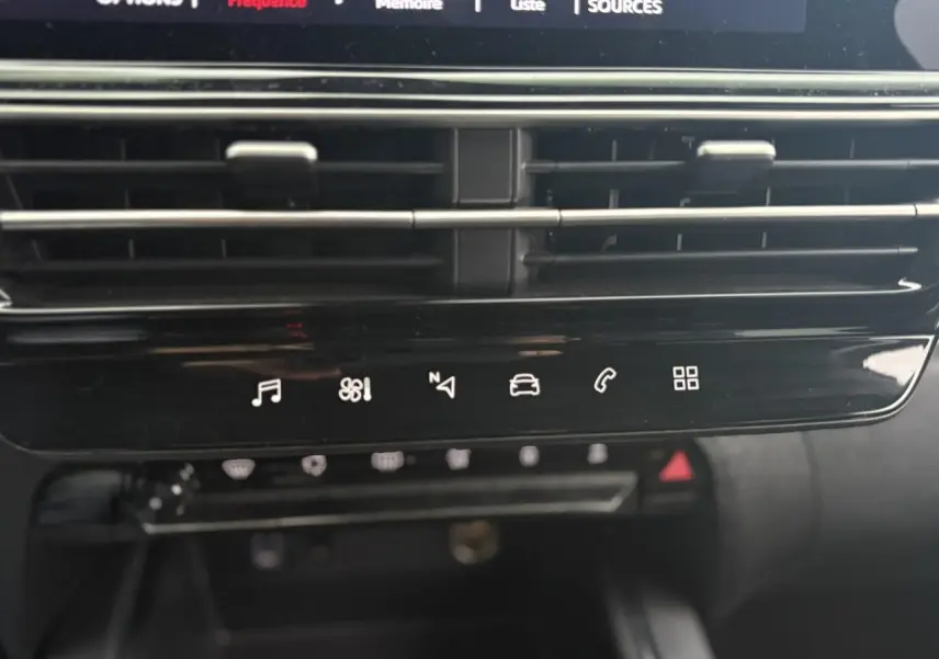 Détail du tableau de bord noir brillant avec commandes tactiles multimédia et climatisation du Citroën C5 Aircross Hybrid 2024.