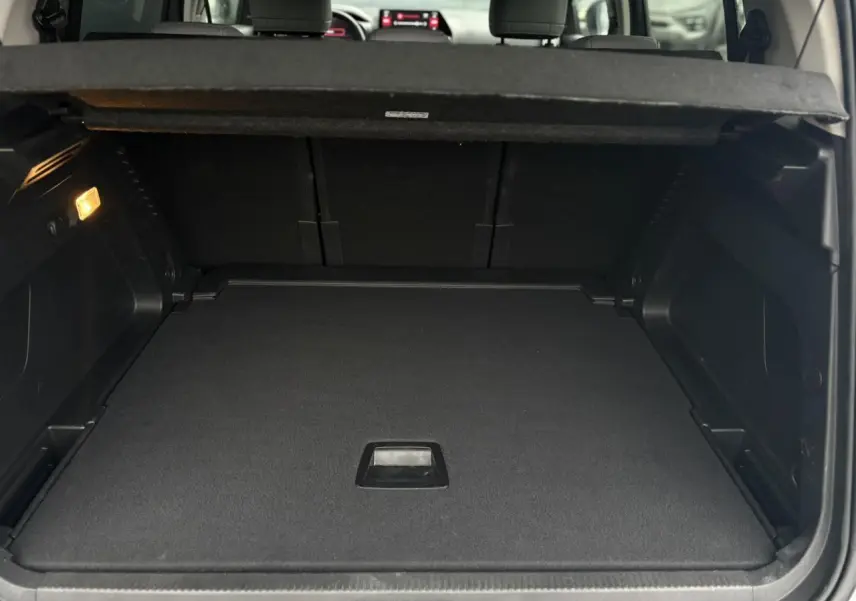 Coffre ouvert vu de l'arrière du Citroën C5 Aircross Hybrid gris Artense avec plancher modulable et habillage noir.