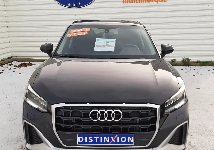 Vue frontale d'un Audi Q2 35 TFSI S-Line noir mito metal avec calandre hexagonale et phares LED allumés.