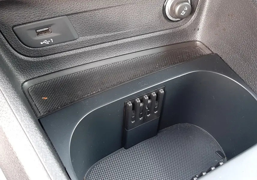 Gros plan sur la console centrale noire de l'Audi Q2 35 TFSI 2023 avec prise USB et allume-cigare 12V visible.