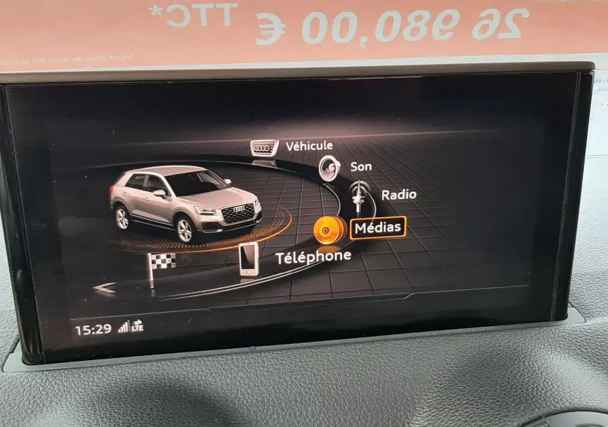 Écran multimédia intérieur montrant le menu principal avec une miniature d'Audi Q2 noir mito metal en vue 3/4 avant.