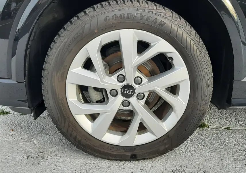 Gros plan sur la roue avant gauche noire mito metal d'un Audi Q2 35 TFSI S-Line avec jante argentée et pneu Goodyear.