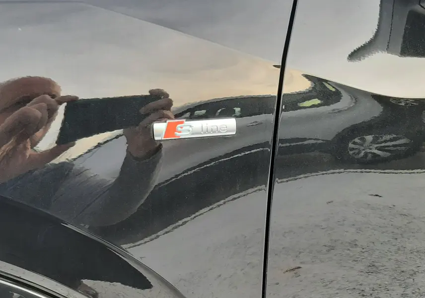 Gros plan sur l'emblème S line sur la portière noire métallisée d'un Audi Q2 2023.