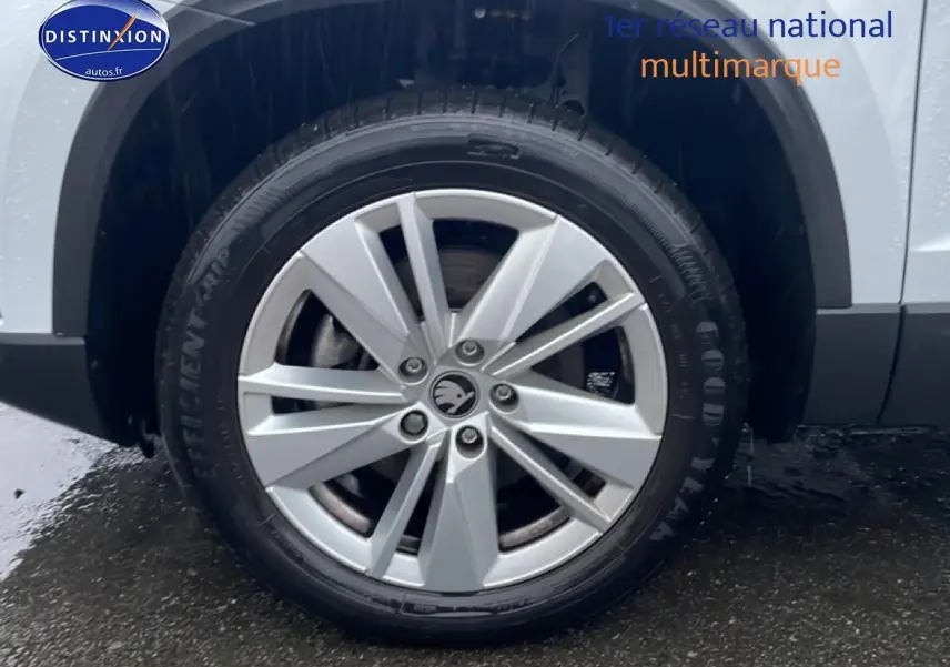 Gros plan sur la roue avant droite avec jante alu argentée du Skoda Karoq blanc glacial 2025.