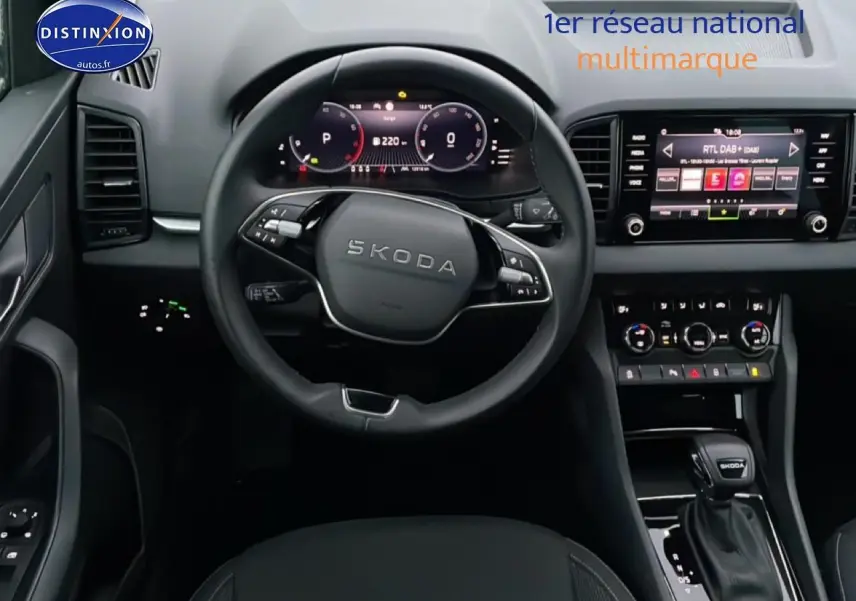 Vue intérieure centrée sur le volant et la console centrale du Skoda Karoq 2025, avec écran tactile et levier de vitesse noir.