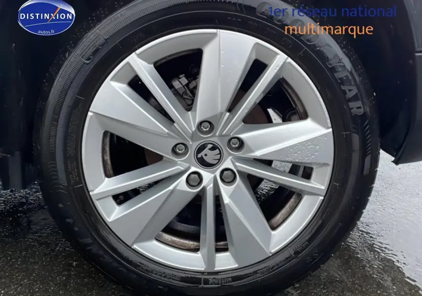 Gros plan sur la jante alu argentée d'un Skoda Karoq blanc glacial, avec pneu Goodyear visible.