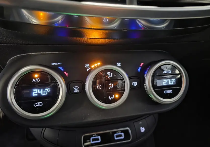 Gros plan sur la console centrale de la Fiat 500X 2024, montrant les commandes de climatisation automatique bi-zone et ports USB arrière.
