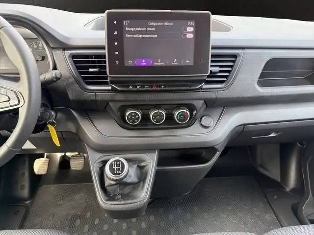 Vue intérieure du tableau de bord du Renault Trafic Fourgon gris, avec écran tactile central et levier de vitesse manuel visible.