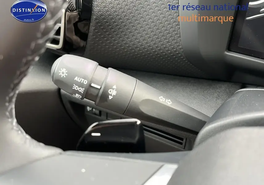 Gros plan sur la manette de clignotants et feux du tableau de bord d'une Citroën C4 noire métal 2025.