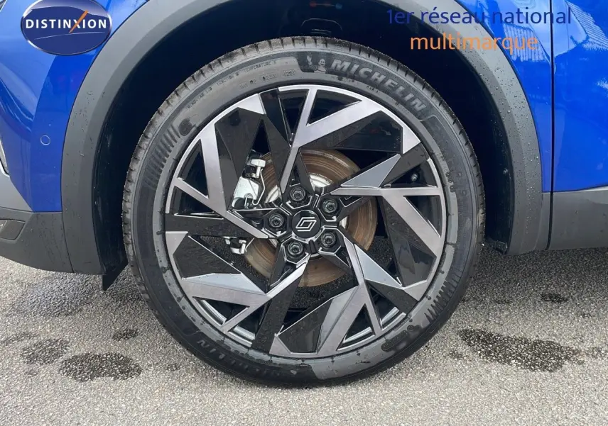 Gros plan sur la roue avant gauche avec jante noire et argent du Renault Captur bleu Iron Metal 2025.