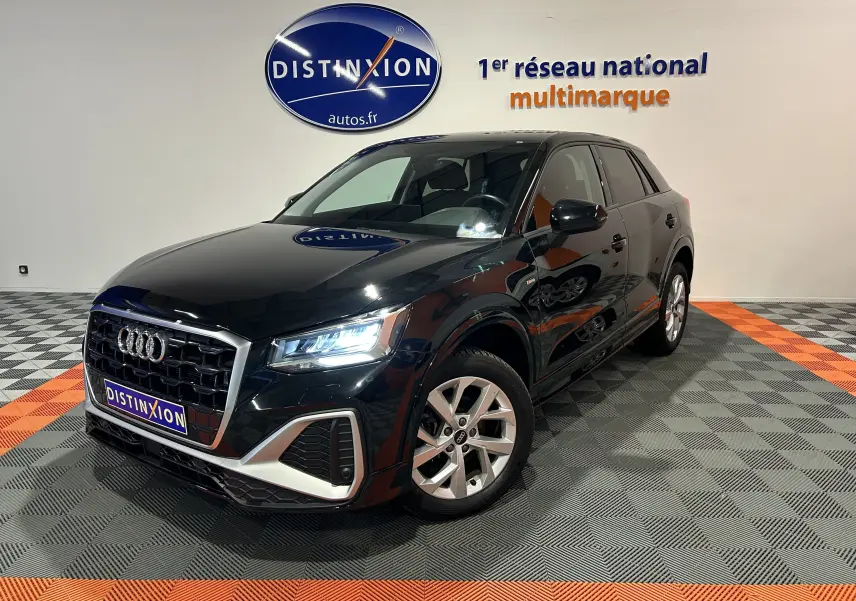 Audi Q2 noir métal vue 3/4 avant droit dans un showroom avec éclairage LED et jantes alliage.