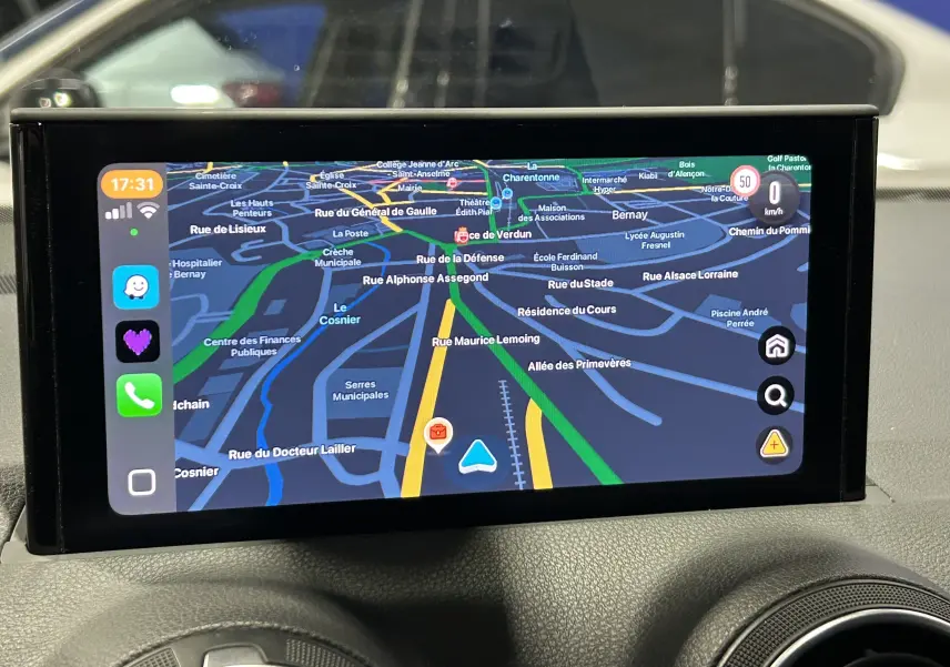 Écran de navigation affichant un Audi Q2 noir métal en 3/4 avant avec menu radio, médias et téléphone.