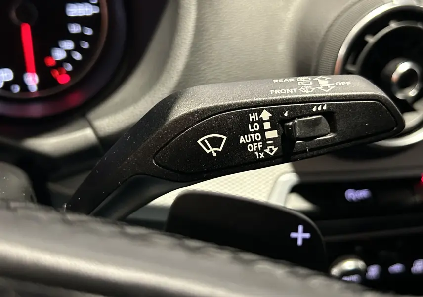 Gros plan sur la commande de régulateur de vitesse à gauche du volant en cuir noir de l'Audi Q2 2023.