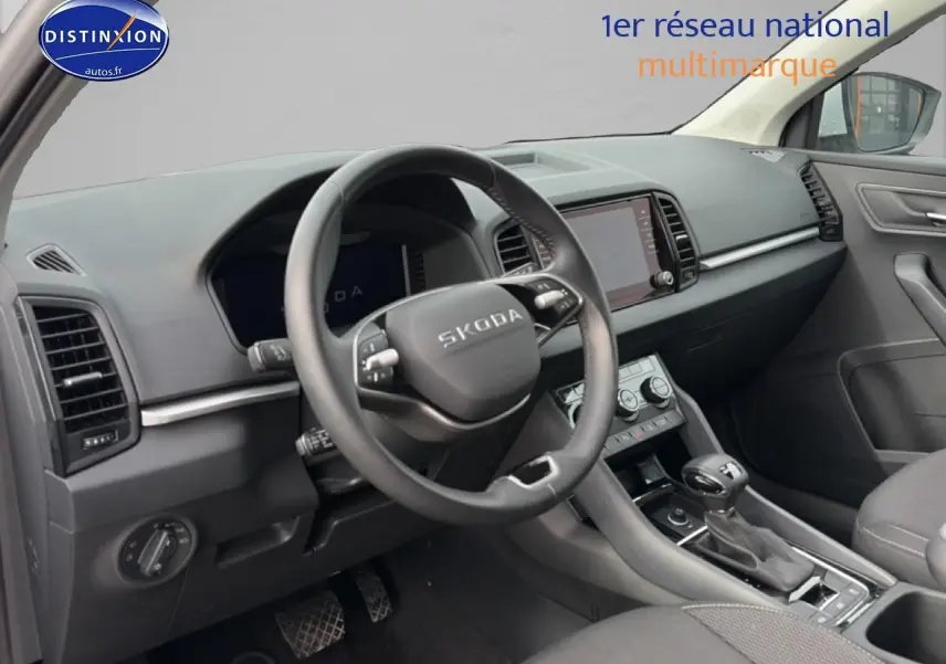 Vue intérieure côté conducteur du tableau de bord et volant cuir noir du Skoda Karoq blanc glacial 2025 avec écran tactile central.