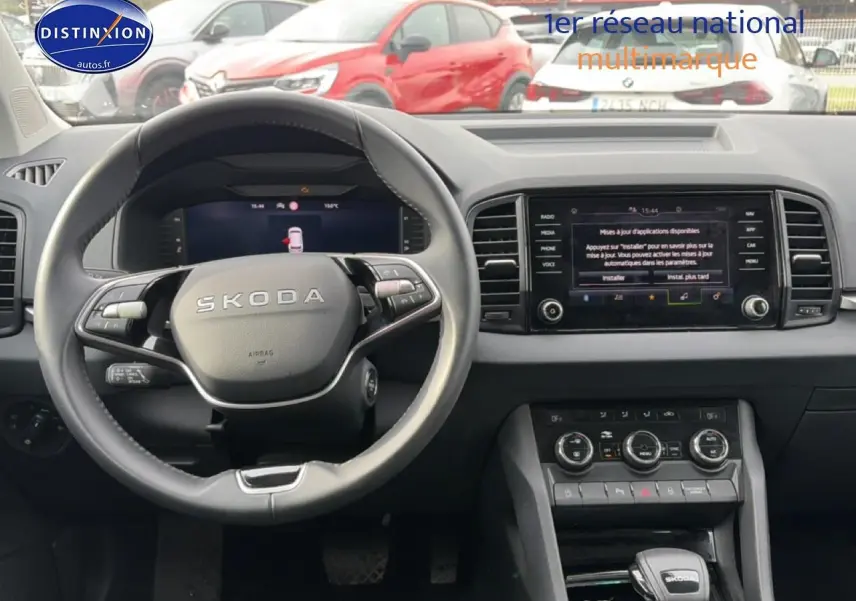 Vue intérieure du tableau de bord et volant cuir du Skoda Karoq blanc glacial, avec écran tactile central allumé.