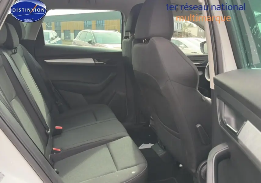 Vue intérieure arrière côté gauche du Skoda Karoq blanc glacial, montrant les sièges et garnitures noires.