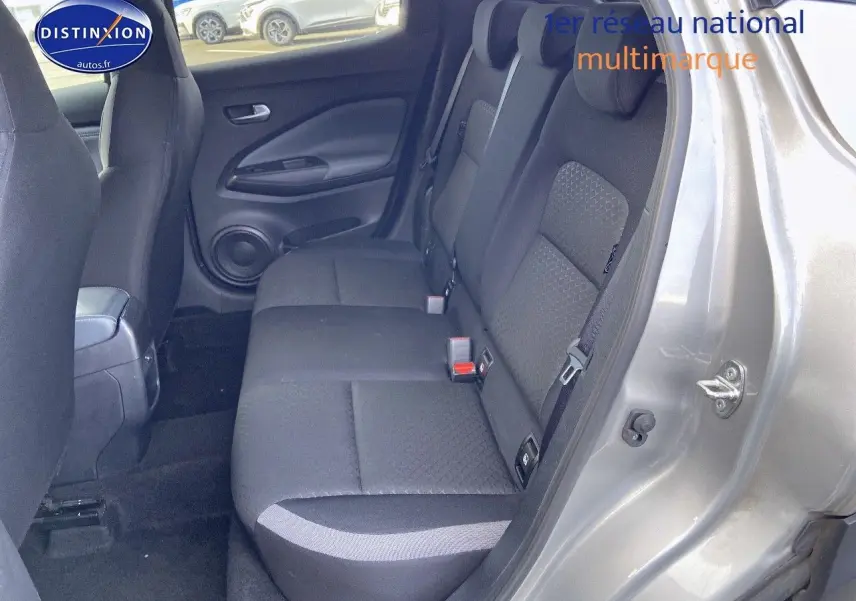 Vue côté droit sur l'intérieur arrière du Nissan Juke gris clair, mettant en valeur les sièges en tissu noir.