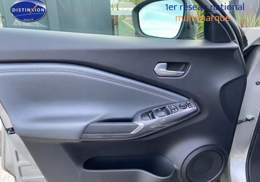 Intérieur de la porte avant gauche du Nissan Juke gris clair 2021, avec commandes électriques et haut-parleur intégré.