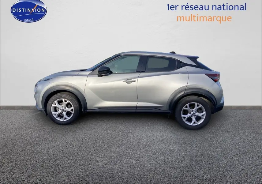 Profil côté gauche d'un Nissan Juke gris clair 2021 avec jantes alliage et protections noires sur les passages de roue.