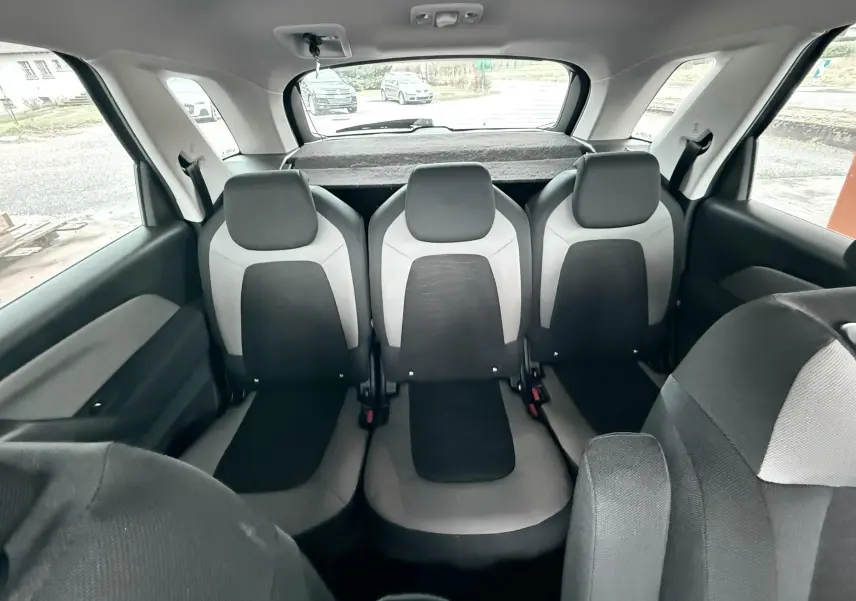 Vue intérieure arrière montrant les trois sièges passagers en tissu bicolore gris et noir d'une Citroën C4 Picasso.