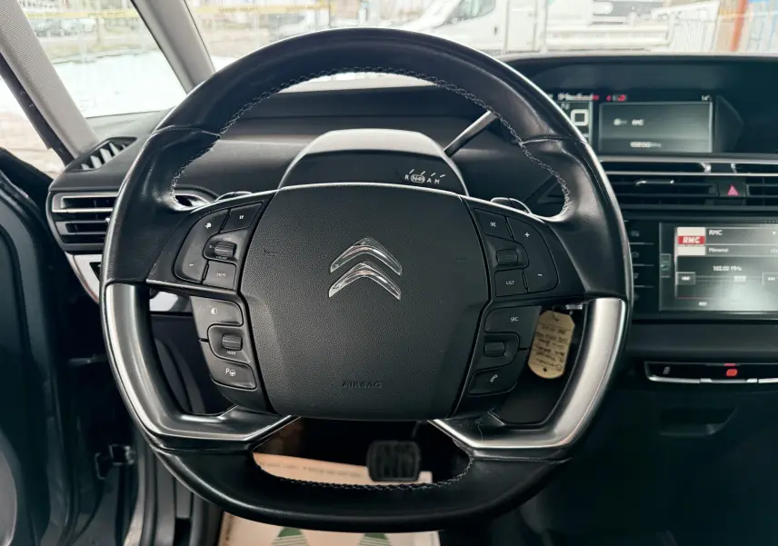 Vue centrée sur le volant noir avec commandes intégrées du Citroën C4 Picasso 2015, intérieur moderne et écran tactile visible.