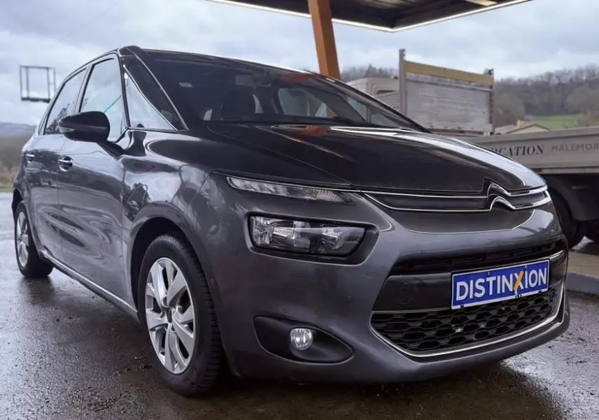 Vue 3/4 avant gauche d'une Citroën C4 Picasso gris platinium métal avec calandre distinctive et plaque Distinxion.