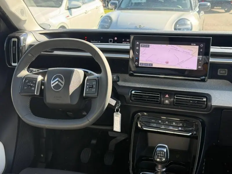 Vue intérieure avant du tableau de bord de la Citroën C3 2025 avec volant multifonction et écran tactile GPS.
