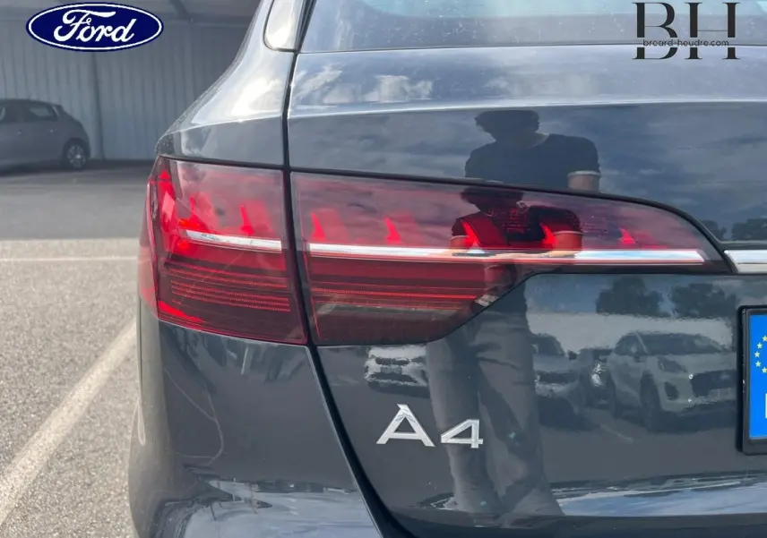 Gros plan sur l'arrière gauche d'une Audi A4 Avant gris Manhattan métallisé avec feux arrière LED et logo A4 visible.