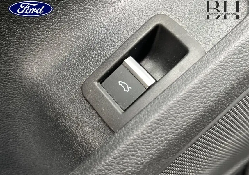 Gros plan sur le bouton d'ouverture du coffre dans l'habitacle d'une Audi A4 Avant gris Manhattan.