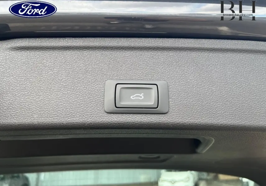 Bouton d'ouverture électrique du coffre sur la partie intérieure du hayon d'une Audi A4 Avant gris Manhattan métallisé.