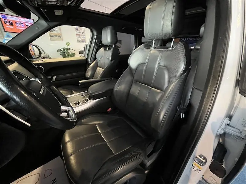 Intérieur du Range Rover Sport blanc 2018, vue côté conducteur sur sièges cuir noir et tableau de bord moderne.