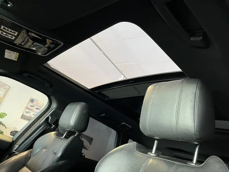 Intérieur du Range Rover Sport 2018 avec sièges cuir noir et toit ouvrant panoramique visible depuis l'avant droit.