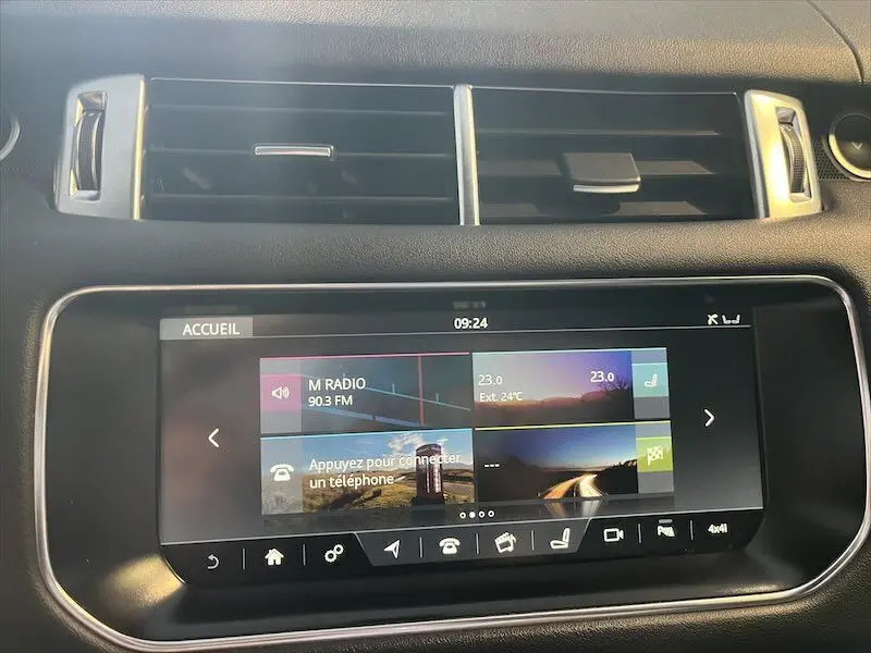 Écran tactile central du tableau de bord du Range Rover Sport blanc, affichant la radio et la température extérieure.