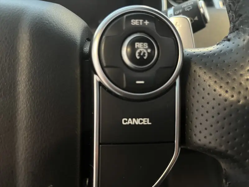 Gros plan sur les commandes de régulateur de vitesse au volant en cuir perforé du Range Rover Sport blanc 2018.