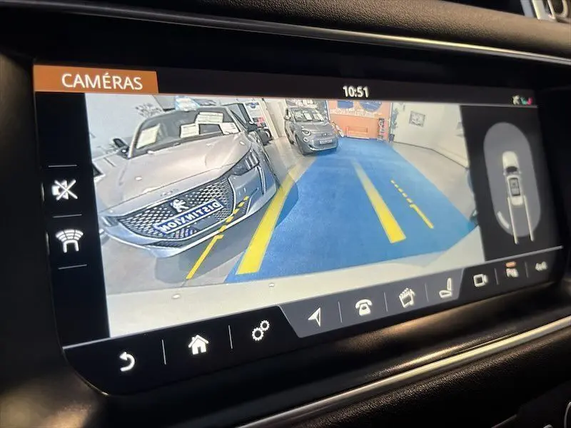 Vue caméra de recul montrant un Range Rover Sport blanc garé en intérieur avec marquages au sol jaunes.