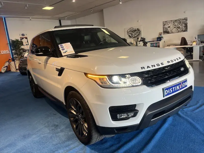 Vue 3/4 avant droite d'un Range Rover Sport blanc avec jantes noires et plaque Distinxion en concession