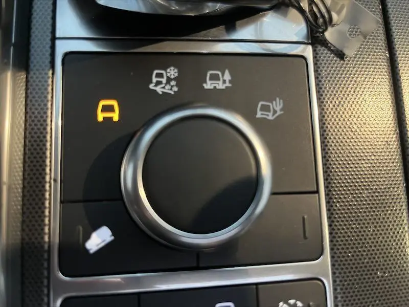 Gros plan sur la molette de sélection des modes de conduite du Range Rover Sport blanc, avec témoin orange allumé.