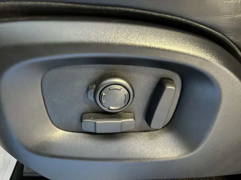 Réglage électrique des sièges noirs dans un Range Rover Sport blanc, vue rapprochée du côté gauche.