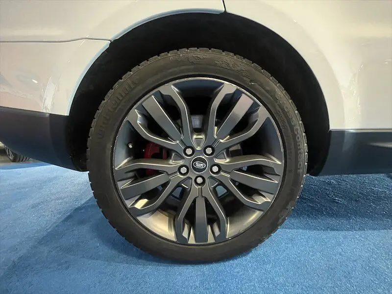 Gros plan sur la roue avant droite du Range Rover Sport blanc de 2018, jante alliage foncé et étrier de frein rouge visible.