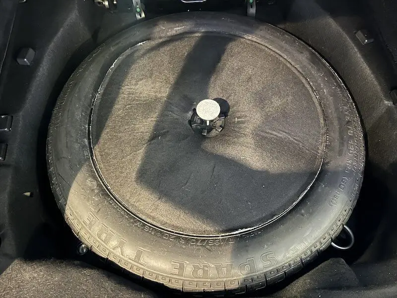 Gros plan sur la roue de secours noire logée dans le coffre du Range Rover Sport blanc de 2018.