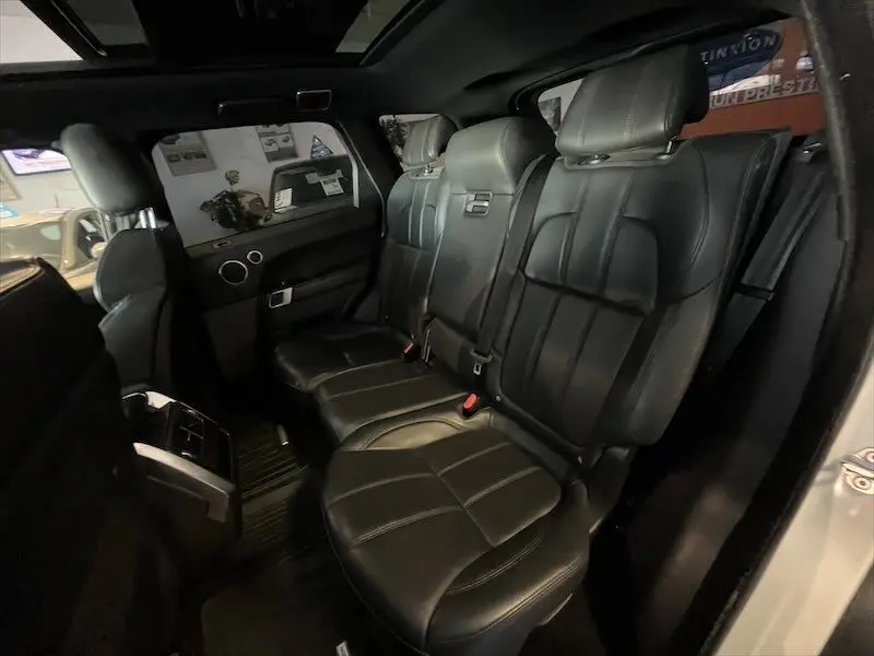 Intérieur arrière du Range Rover Sport blanc 2018, sièges en cuir noir avec ceintures de sécurité visibles côté droit.