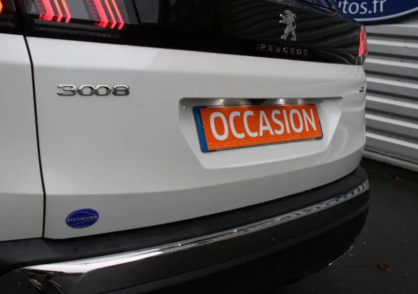 Gros plan sur l'arrière blanc nacré d'une Peugeot 3008 avec plaque orange "OCCASION" et logo noir brillant.