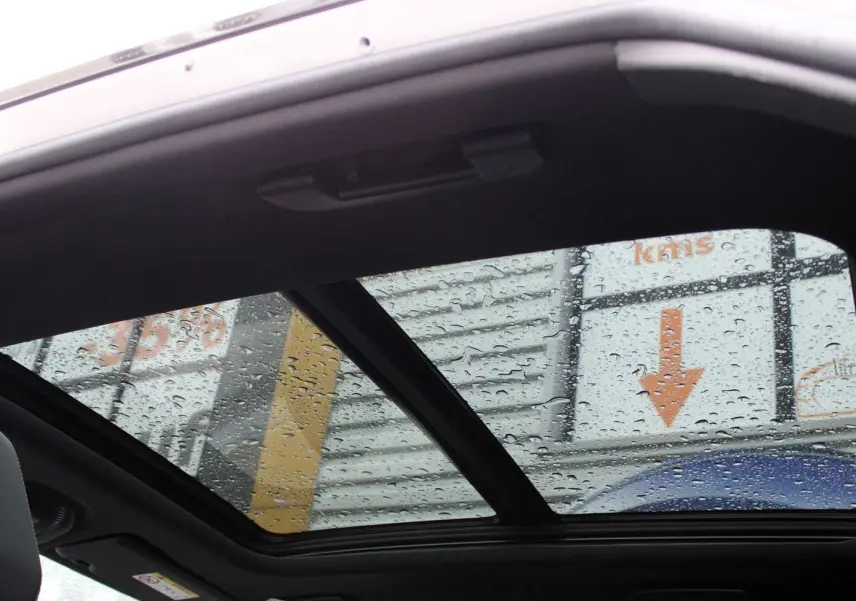 Toit panoramique ouvrant avec gouttes de pluie visible depuis l'intérieur d'un Peugeot 3008 blanc nacré 2025.